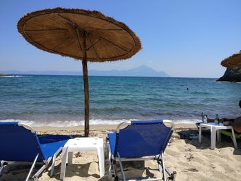 Deck chairs on beach against blue sky