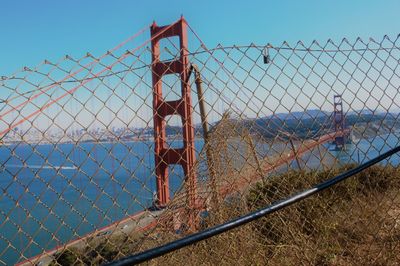 Man seen through chainlink fence against clear sky