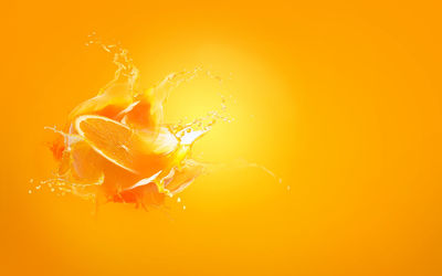 Close-up of water splashing against orange background
