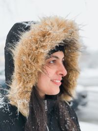 Close-up of smiling young woman wearing hood during winter