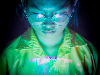 Portrait of young man wearing eyeglasses against black background