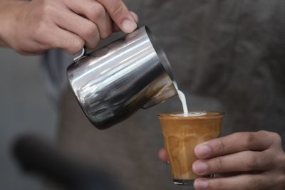 Cropped image of hand pouring tea cup