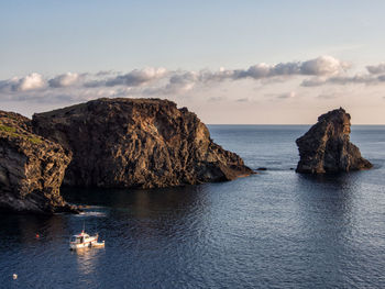 Rock formation in sea against sky