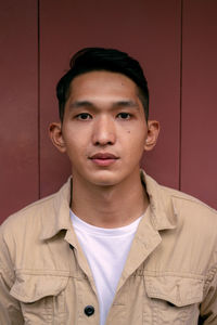 Portrait of young man standing against yellow wall
