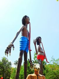 Low angle view of young couple against trees against clear sky