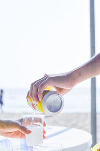 Midsection of person holding drink against sea