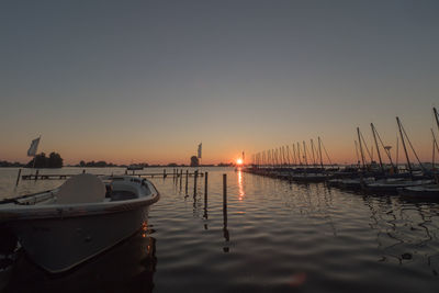 Boats moored at lake against sky during sunset