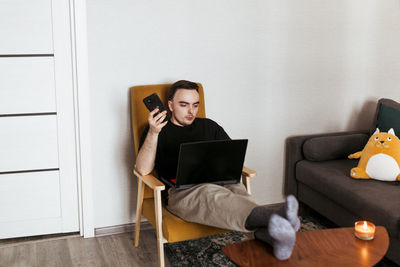 Young woman using laptop while sitting on sofa at home
