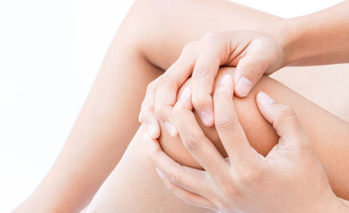 Close-up of woman touching hand over white background