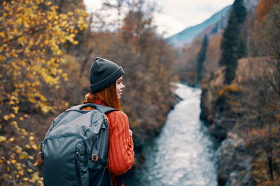 Rear view of person standing on rock during autumn