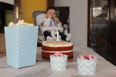 Close-up of cake with baby sitting at background