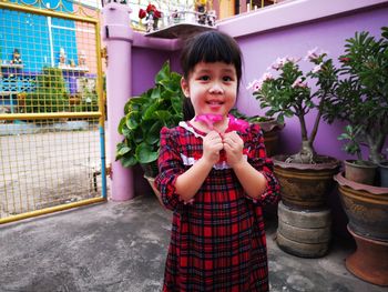 Portrait of cute girl standing on potted plant flower