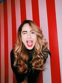 Portrait of beautiful young woman standing against red wall