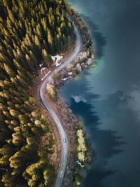 Aerial view of winding road with blue lake. great road trip trough the dense woods.