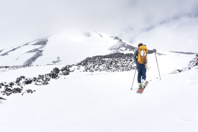 Rear view of hiker on snow against sky