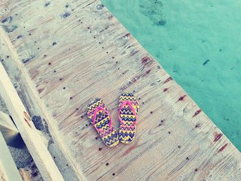 Close-up of flip-flop on pier over sea
