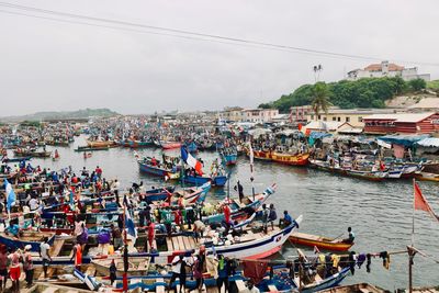 Boats moored in harbor by sea against sky