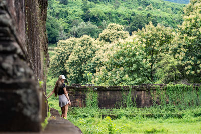 Rear view of woman standing by lake in forest