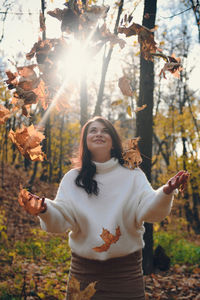 Full length of young woman standing in forest during autumn