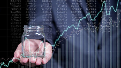 Digital composite image of businessman holding jar by graph chart