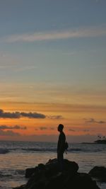 Silhouette man looking at sea against sky during sunset