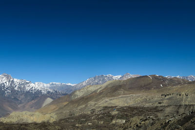 Scenic view of snowcapped mountains against clear blue sky