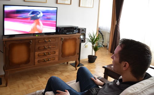 High angle view of man watching television while sitting on sofa at home