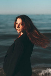 Portrait of young woman standing at beach