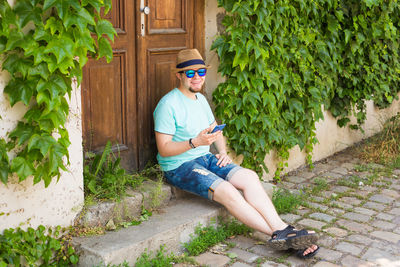 Full length of man sitting on chair against plants