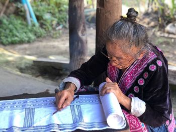 High angle view of senior woman manufacturing fabric on table