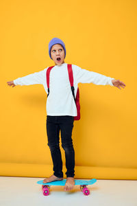 Portrait of girl standing against yellow background