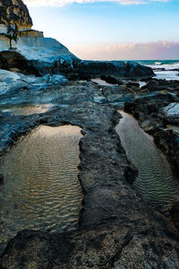 Scenic view of rocks on beach against sky