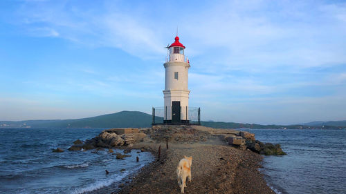 Lighthouse by sea against sky