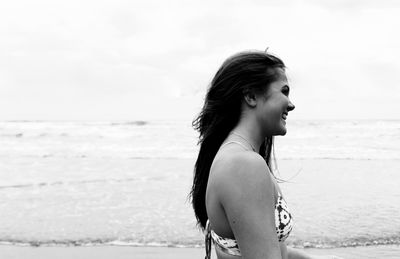 Close-up of young woman at beach against sky