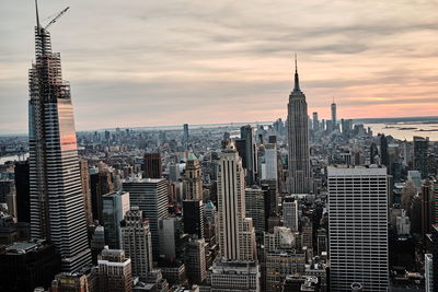 Aerial view of buildings in city against cloudy sky