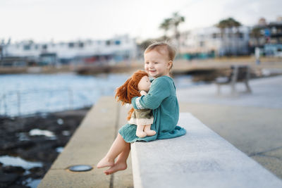 Side view of girl sitting on retaining wall