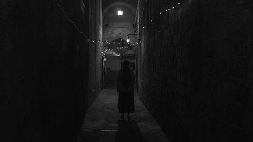 Rear view of person walking on street in illuminated building