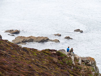 People standing on rock by sea