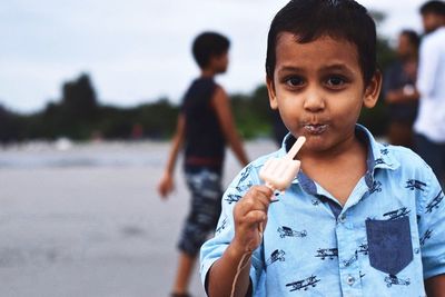 Close-up of boy eating ice cream while standing at beach