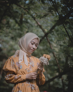 Woman standing by tree against plants