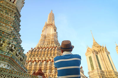 Closeup a man capturing photo of wat arun central prang, the iconic landmark of bangkok, thailand