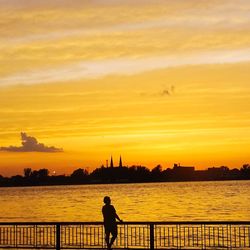 Silhouette man standing by sea against sky during sunset