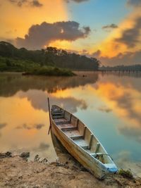 Boat moored on beach against sky during sunset