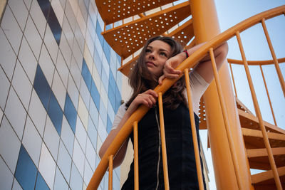 Low angle view of woman standing on steps against sky