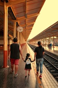 Rear view of people walking on railway bridge