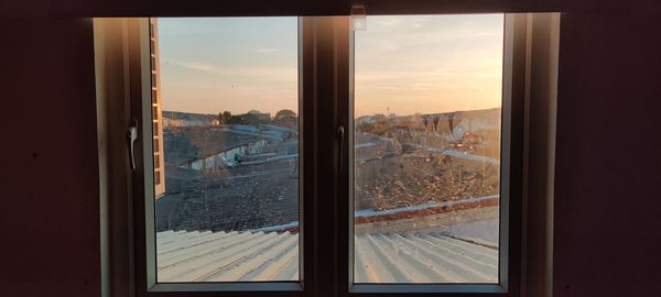 Panoramic view of city seen through window during sunset
