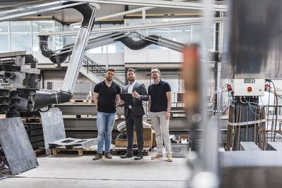 Three men standing and talking on factory shop floor