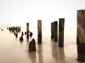 Panoramic view of wooden posts in sea against clear sky