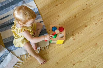 High angle view of baby playing with toy on floor at home