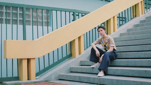 Side view of young couple sitting on staircase against building